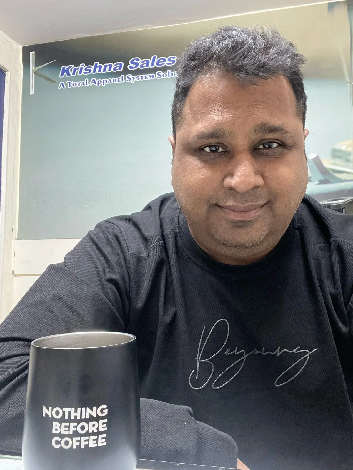 Mayank, founder of Krishna Sales, in front of the company's Total Apparel System Solutions signage